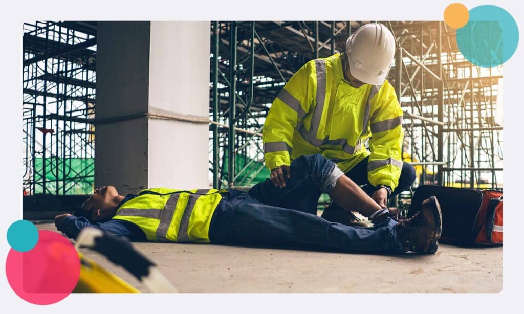 An injured construction worker receiving first aid from a colleague
