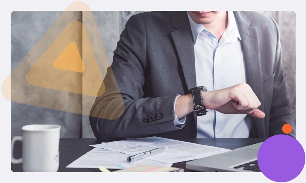 An employee at a desk looking at the time on their watch