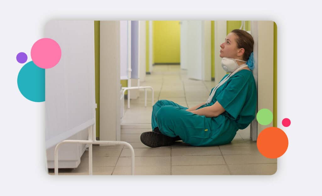 A doctor sitting on the floor alone in a hospital corridor