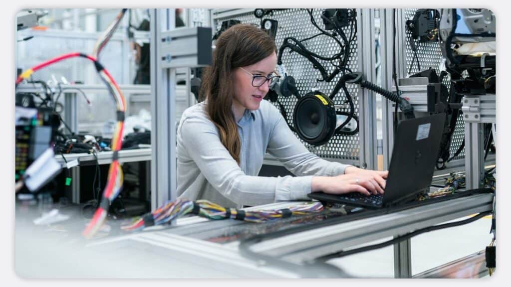 A test engineer using a laptop surrounded by test equipment