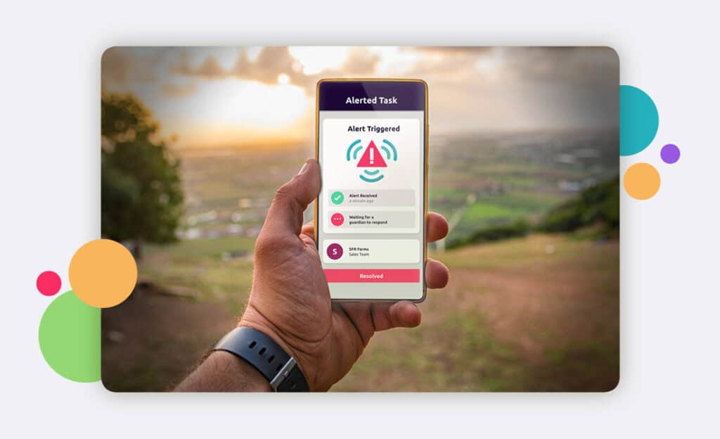 Safepoint app on a smartphone held in a hand by a person in lone working in the countryside