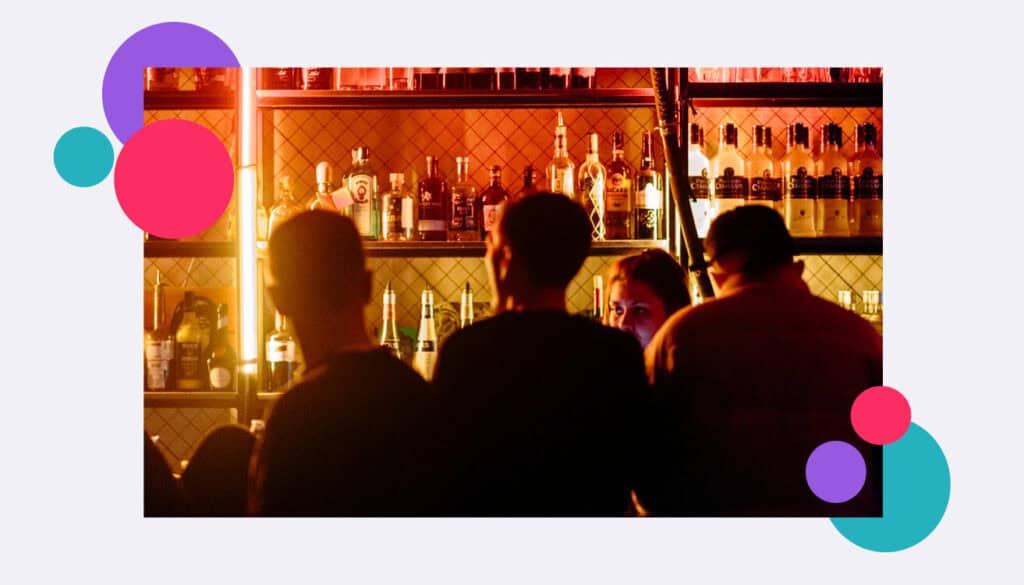 A photo of a lone working bar staff member at a busy venue