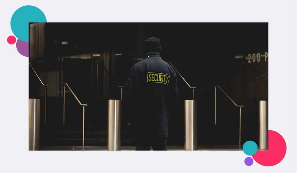A security guard standing outside the entrance to a large building