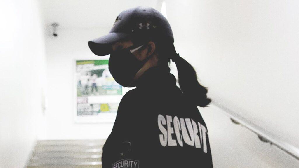 A security guard wearing a hat alone on a stairwell