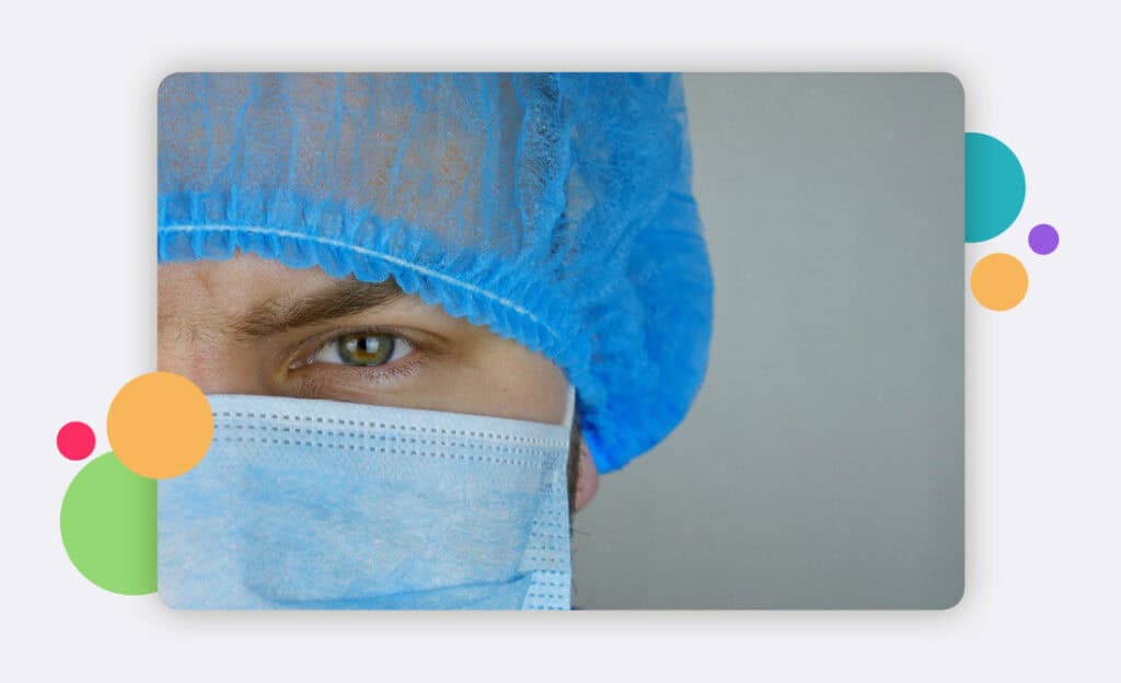 A doctors face with a hair and face PPE covering