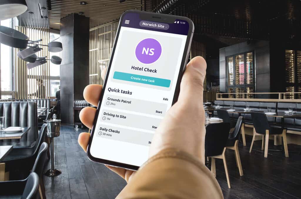 A hand holding a smartphone in a hotel demonstrating the use of the safepoint lone worker app in a hospitality setting