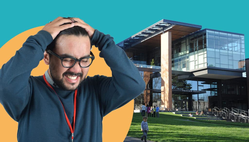 A university staff member stressed with their hands on their head in front of a university building